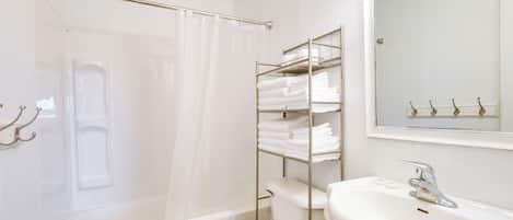 Un bany amb una banyera blanca, un vàter, un lavabo i un penjador de tovalloles.
