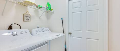 A laundry area with a washing machine, dryer, and a mop leaning against the wall.