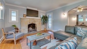 A living room with a stone fireplace, a sofa, a chair, and a coffee table. - Vacation Rental Near University of Illinois (Champaign)