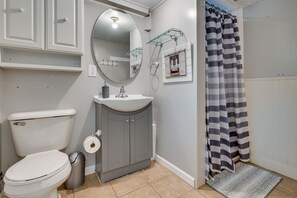 A bathroom with a toilet, sink, mirror, and striped shower curtain.