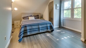 A bedroom with a bed, bedside table, and a window with curtains. - Vacation Rental Near University of Illinois (Champaign)