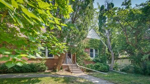 A brick house with a front porch, a staircase leading to the entrance, and a well-maintained lawn. - Vacation Rental Near University of Illinois (Champaign)