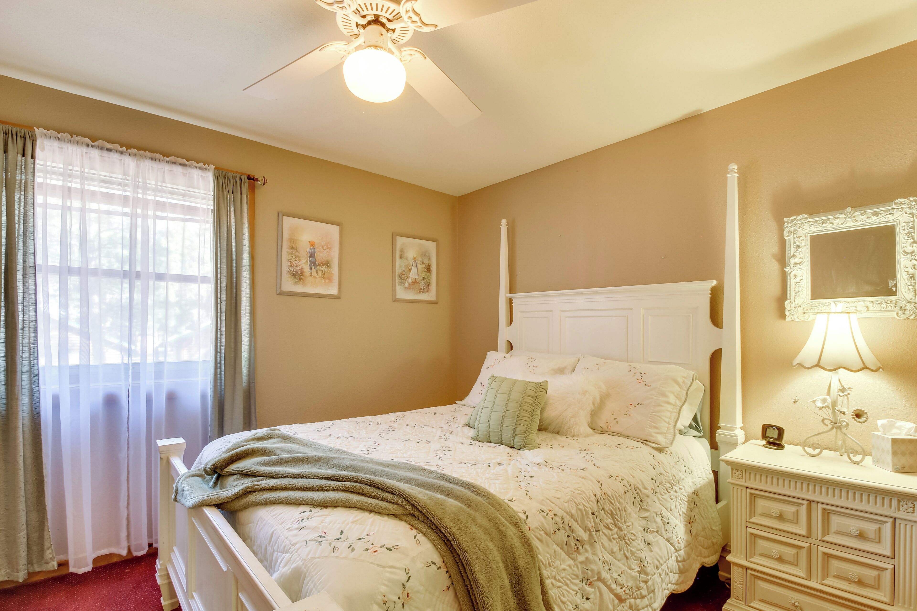 Un dormitorio con cama, cómoda, espejo y ventilador de techo.