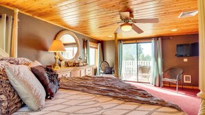 Ein Schlafzimmer mit einem großen Bett, einem Deckenventilator, einer Chandelierleuchtre und Blick ins Freie.