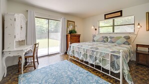 A bedroom with a bed, a desk, a chair, a dresser, and a window with curtains.