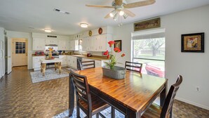 A spacious kitchen with white cabinets, a wooden dining table, and a ceiling fan.