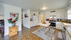 A modern kitchen with white cabinets, a central island, and a dining area.