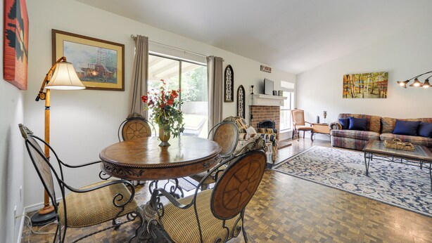 A dining area with a round table and chairs, a vase with flowers, and a lamp.