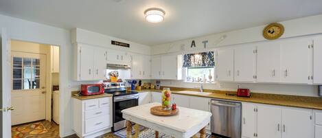 A modern kitchen with white cabinets, a wooden floor, and a central island with a fruit bowl.