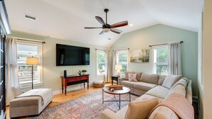 Ein Wohnzimmer mit Sofa, Hocker, Couchtisch und Deckenventilator.