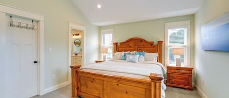 A bedroom with a wooden bed, two nightstands, a dresser, a coat rack, and a window with blinds.
