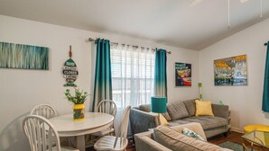 A living room with a grey sofa, a white dining table with chairs, a blue lamp, and a painting on the wall. - Lakefront Keystone Heights Home w/ Boat Ramp! (Keystone Heights)