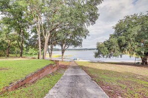 A concrete pathway leading to a body of water, surrounded by trees and grassy areas. - Lakefront Keystone Heights Home w/ Boat Ramp! (Keystone Heights)