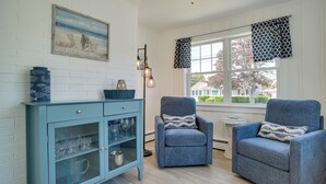 A room with a light blue cabinet with glass doors, two matching armchairs, a small table, and a window with patterned curtains. - Newly Renovated Dennis Port Home: Close to Beaches (Dennis Port)