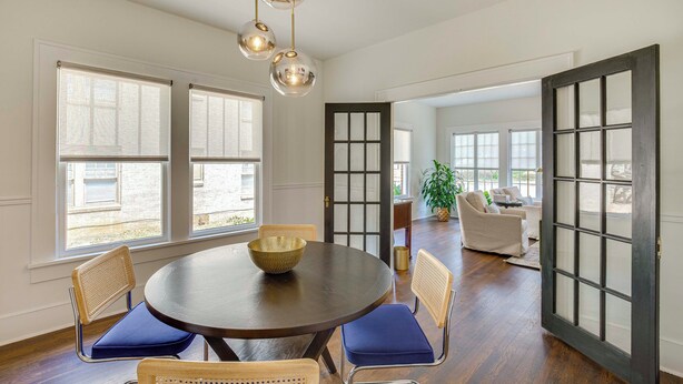 A dining area with a round table, chairs, and a bowl. There are windows and a door with glass panels. - Walk to Bergfeld Park: 1928 Azalea District Home (Tyler)