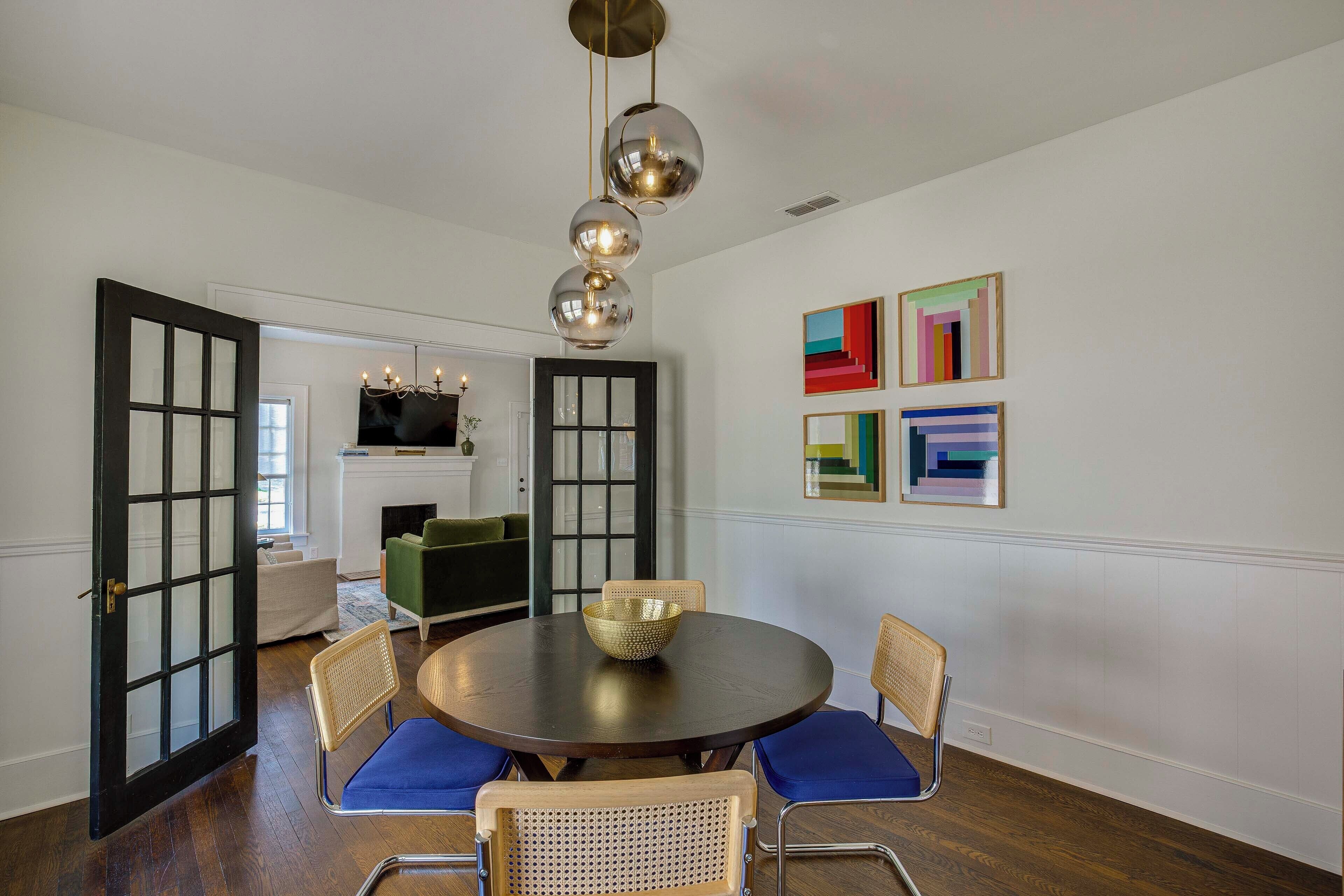 A dining area with a round table, chairs, and a chandelier.
