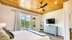 Ein Schlafzimmer mit einem großen Bett, einem Deckenventilator, einem Fernseher und einer Kommode.