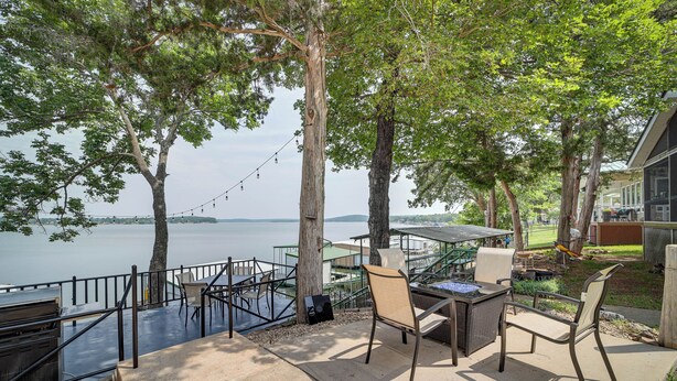 Une terrasse extérieure avec un barbecue, des sièges et une vue sur le lac.
