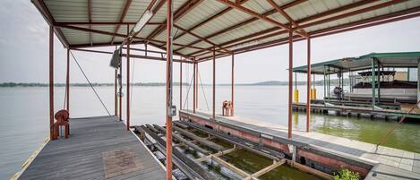 A covered dock with a wooden deck, metal railings, and a small bench.