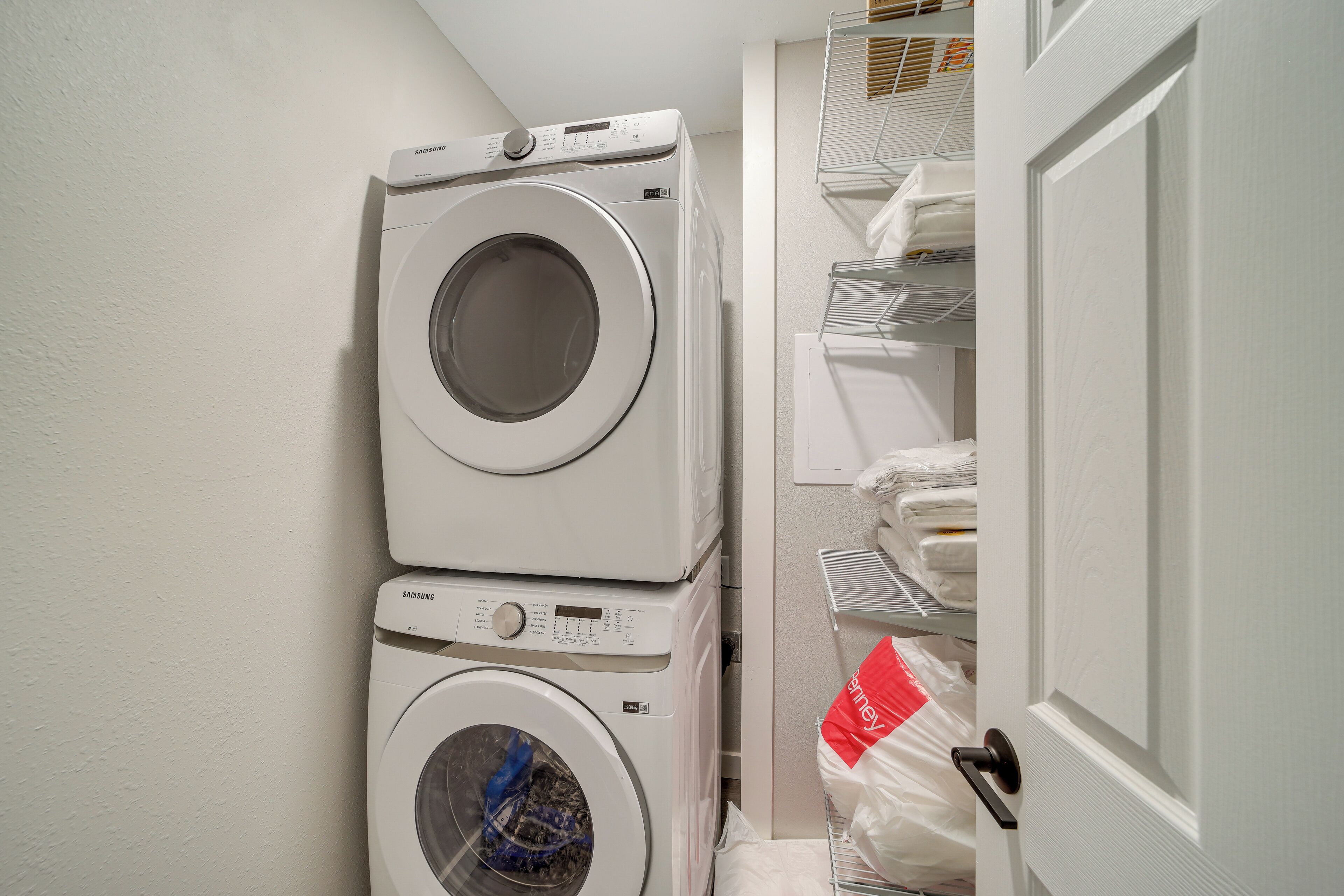 A laundry room with two stacked washing machines and a drying rack with folded towels.