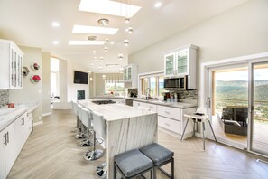 A modern kitchen with a large island, bar stools, and a view of the outdoors. - Prescott Gem: Hot Tub & Mtn Views, 7 Mi to Dtwn (Prescott)