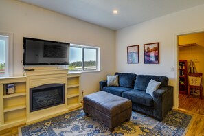 A living room with a fireplace, a television, a couch, and a rug. - Port Angeles Apartment Near Olympic Natl Park! (Port Angeles)