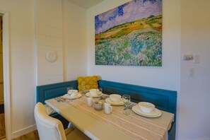 A dining area with a table set for four, a blue bench, and a painting on the wall. - Port Angeles Apartment Near Olympic Natl Park! (Port Angeles)