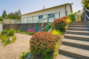 A building with a stone wall, a concrete pathway, and a set of stairs leading to a green metal railing. - Port Angeles Apartment Near Olympic Natl Park! (Port Angeles)