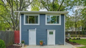 A two-story house with a front porch, a small garden, and a wooden fence.