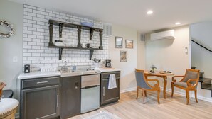 A modern kitchen with a built-in oven, a coffee maker, and a small dining area with two chairs and a table.