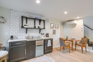 Una cocina moderna con horno empotrado, cafetera y un pequeño comedor con dos sillas y una mesa.