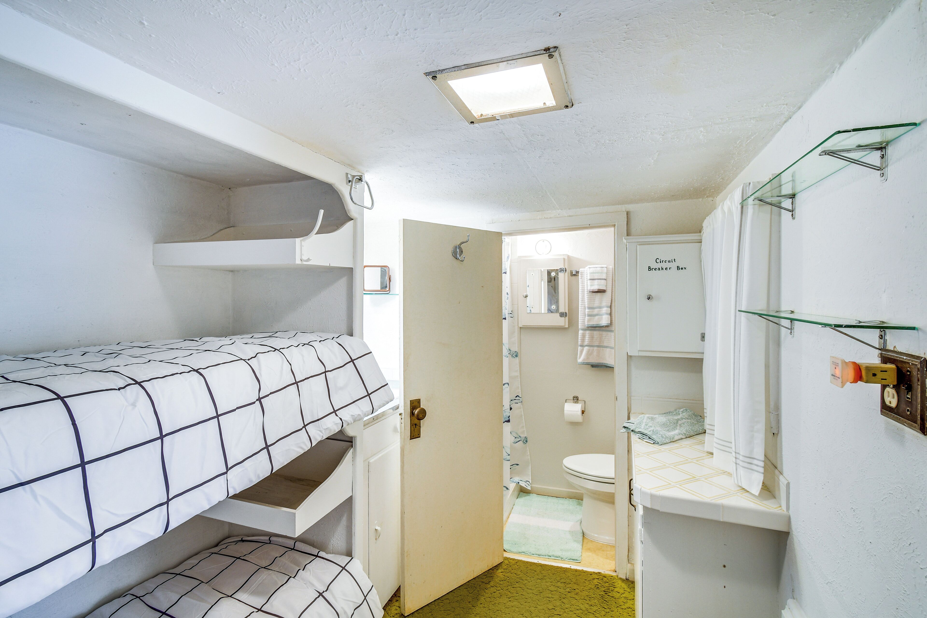 A compact room with bunk beds, a toilet, and a shower area.