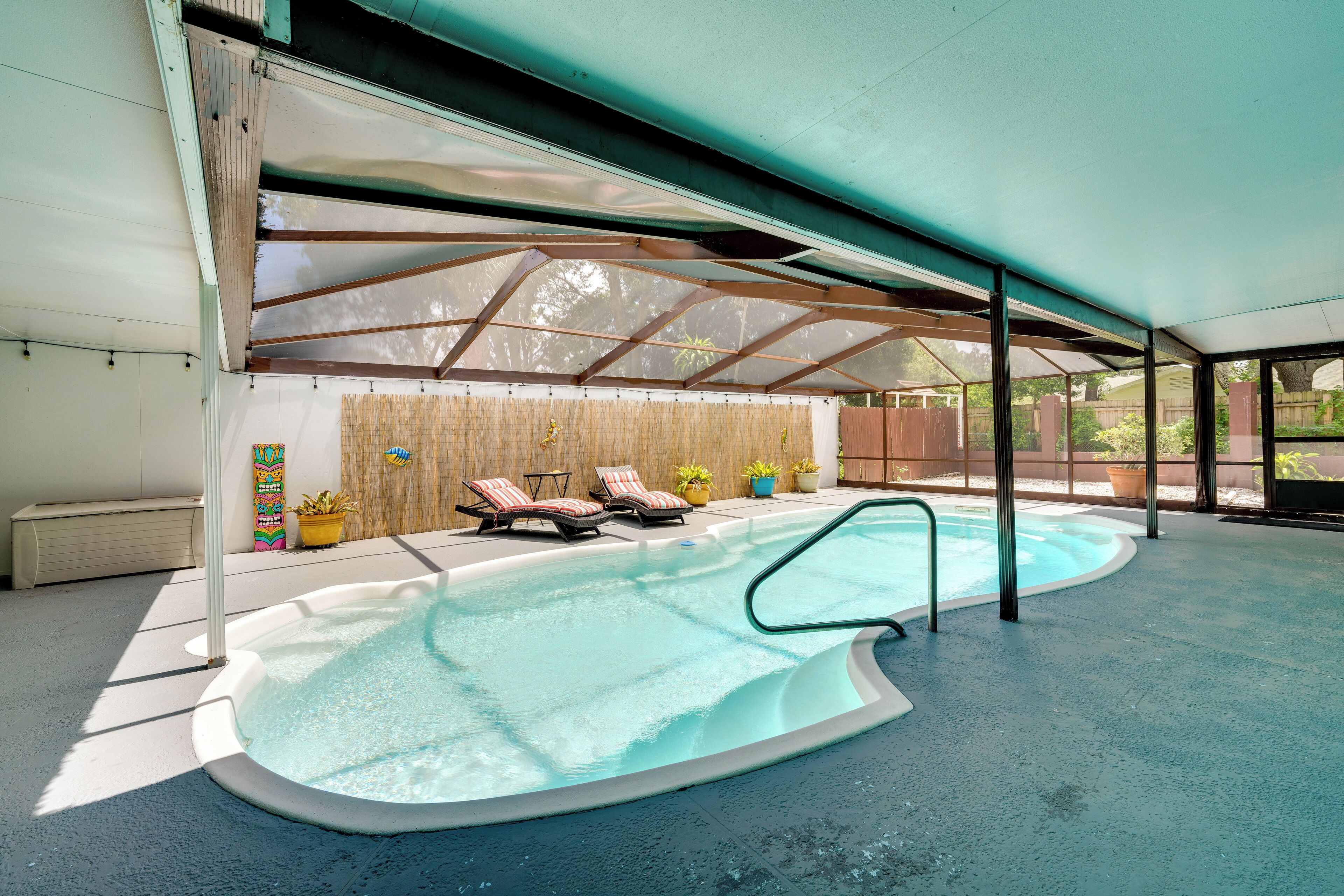 An indoor swimming pool with lounge chairs and a covered area.