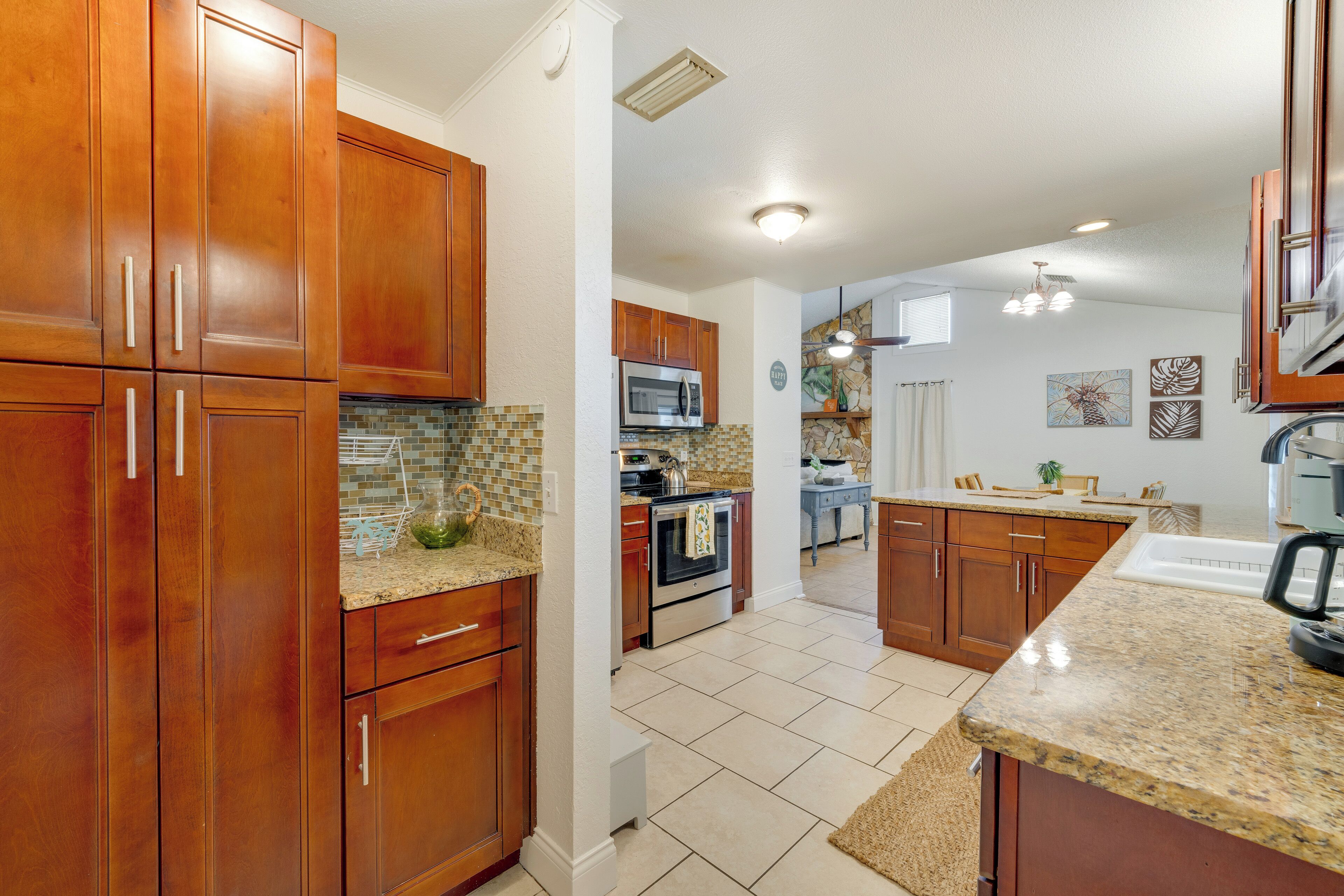 A kitchen with wooden cabinets, a microwave, an oven, and a granite countertop.