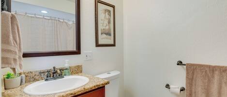 Un baño con lavamanos, espejo, inodoro y toallero.