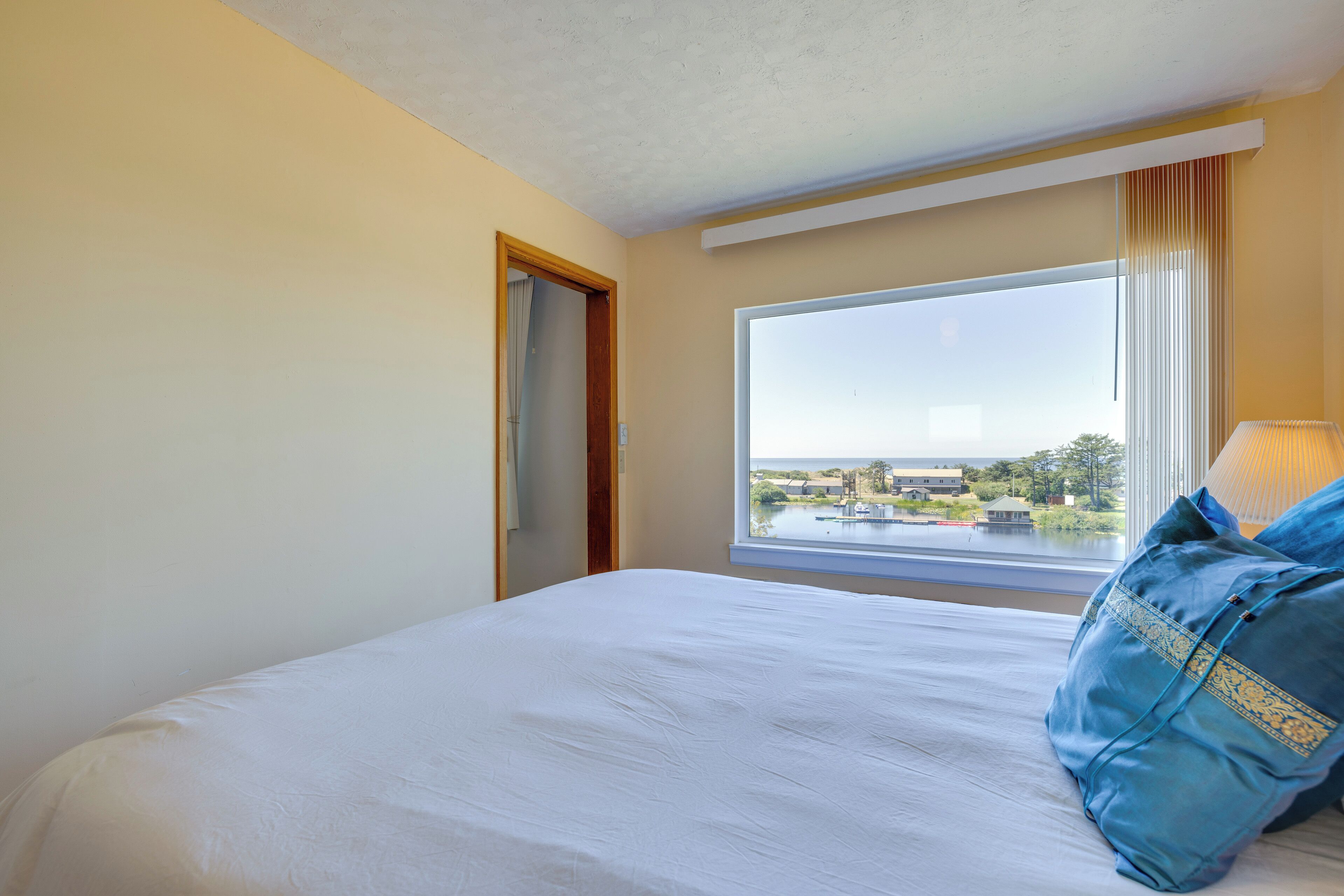 A hotel room with a large bed, a window with a view of the outdoors, and a door.