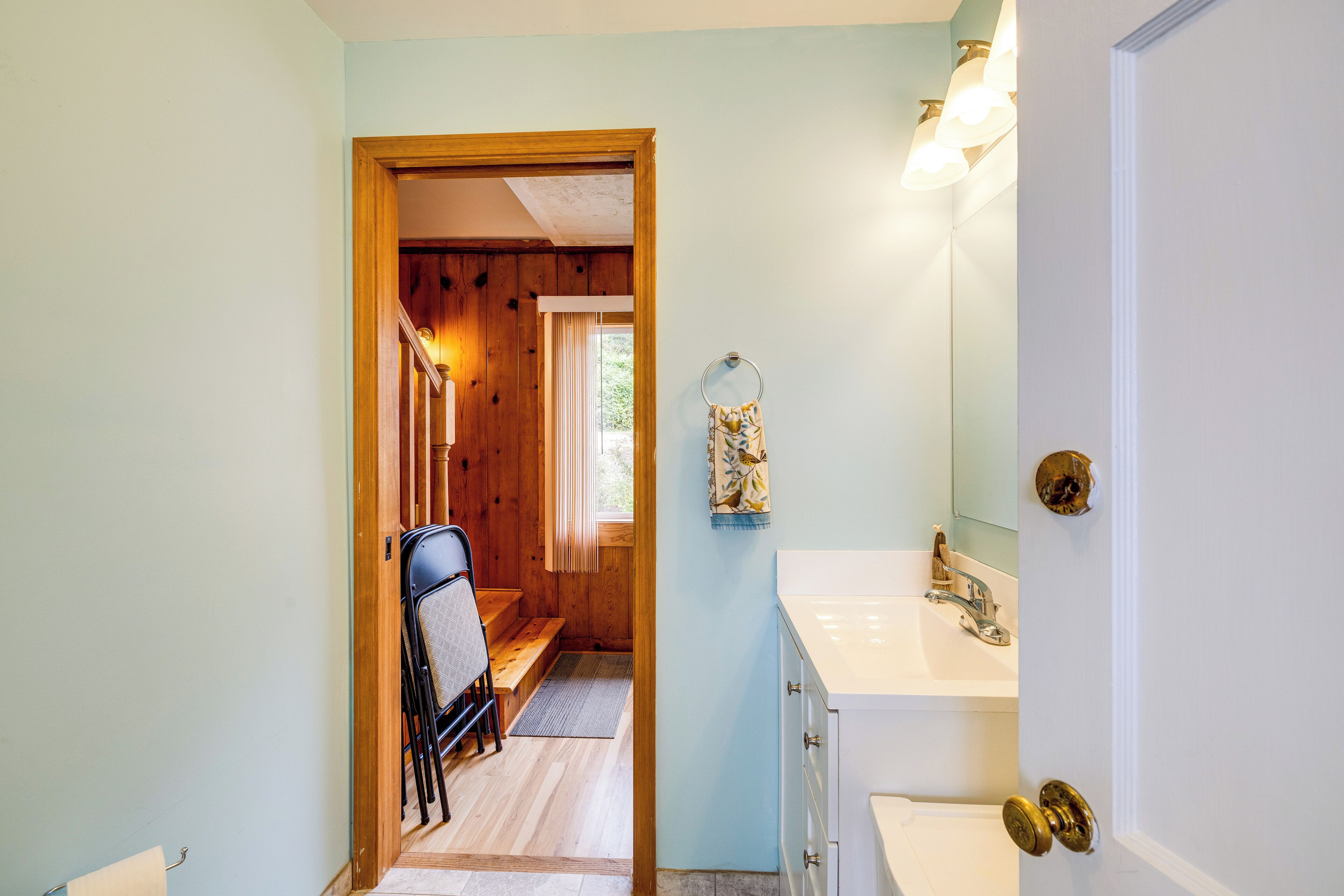 A bathroom with a sink, mirror, and wooden door.