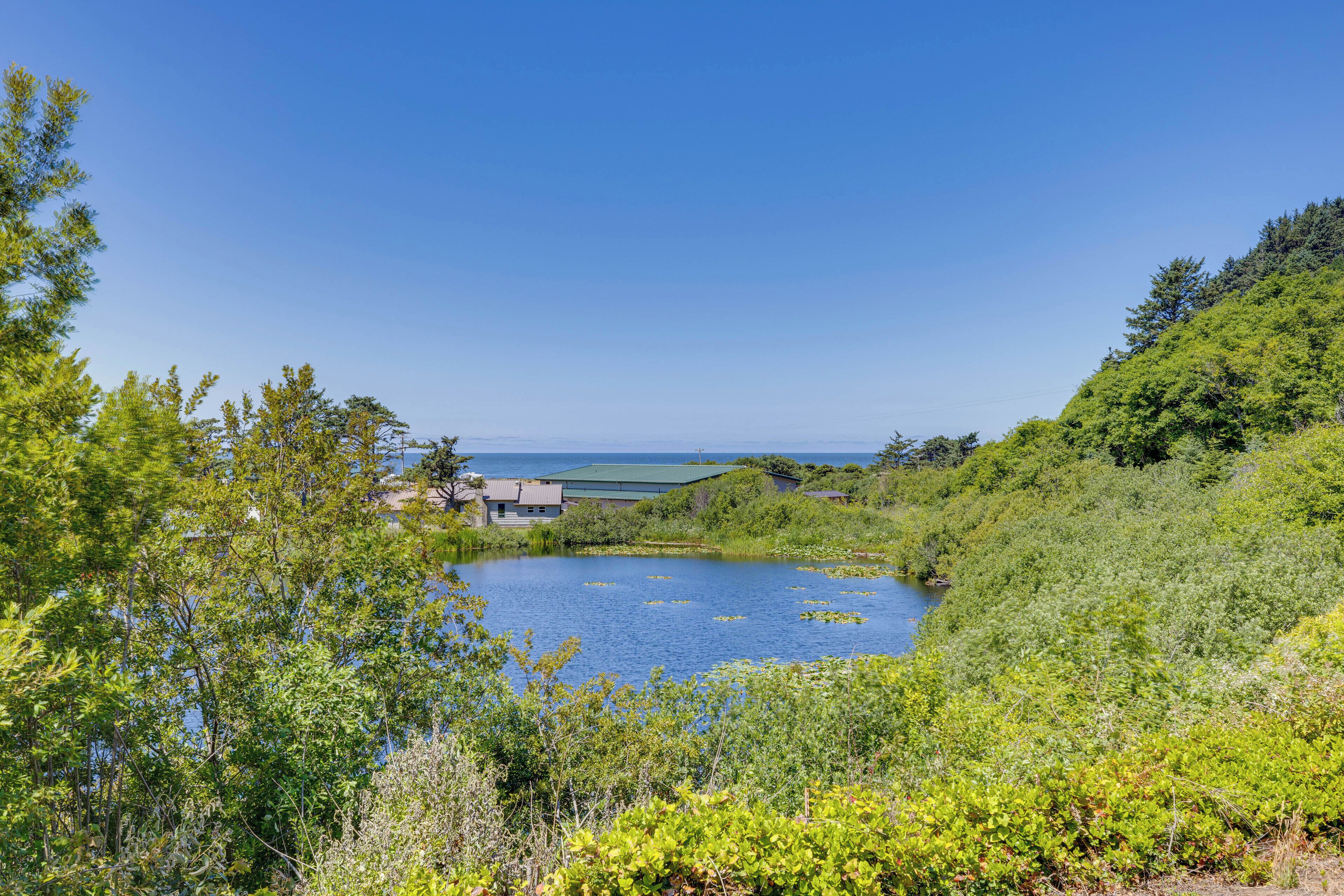 A lakeside property with a house surrounded by lush greenery and a clear view of the water.