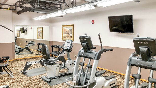 A gym with various exercise equipment, including treadmills and elliptical machines.