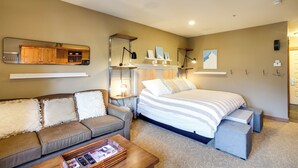 A hotel room with a bed, a sofa, a coffee table, a mirror, and a small cabinet.