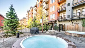 A residential building with a swimming pool, outdoor seating, and a covered grill area.