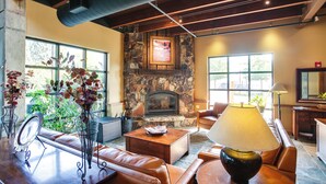 A cozy living room with a stone fireplace, leather sofas, and a coffee table.