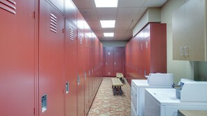 A locker room with red lockers, a bench, and a washing machine.
