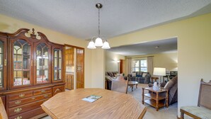 Un salón espacioso con una mesa de comedor de madera, un aparador grande con puertas de cristal y una araña.