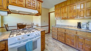 Una cocina con armarios de madera, estufa a gas, horno empotrado y cafetera.