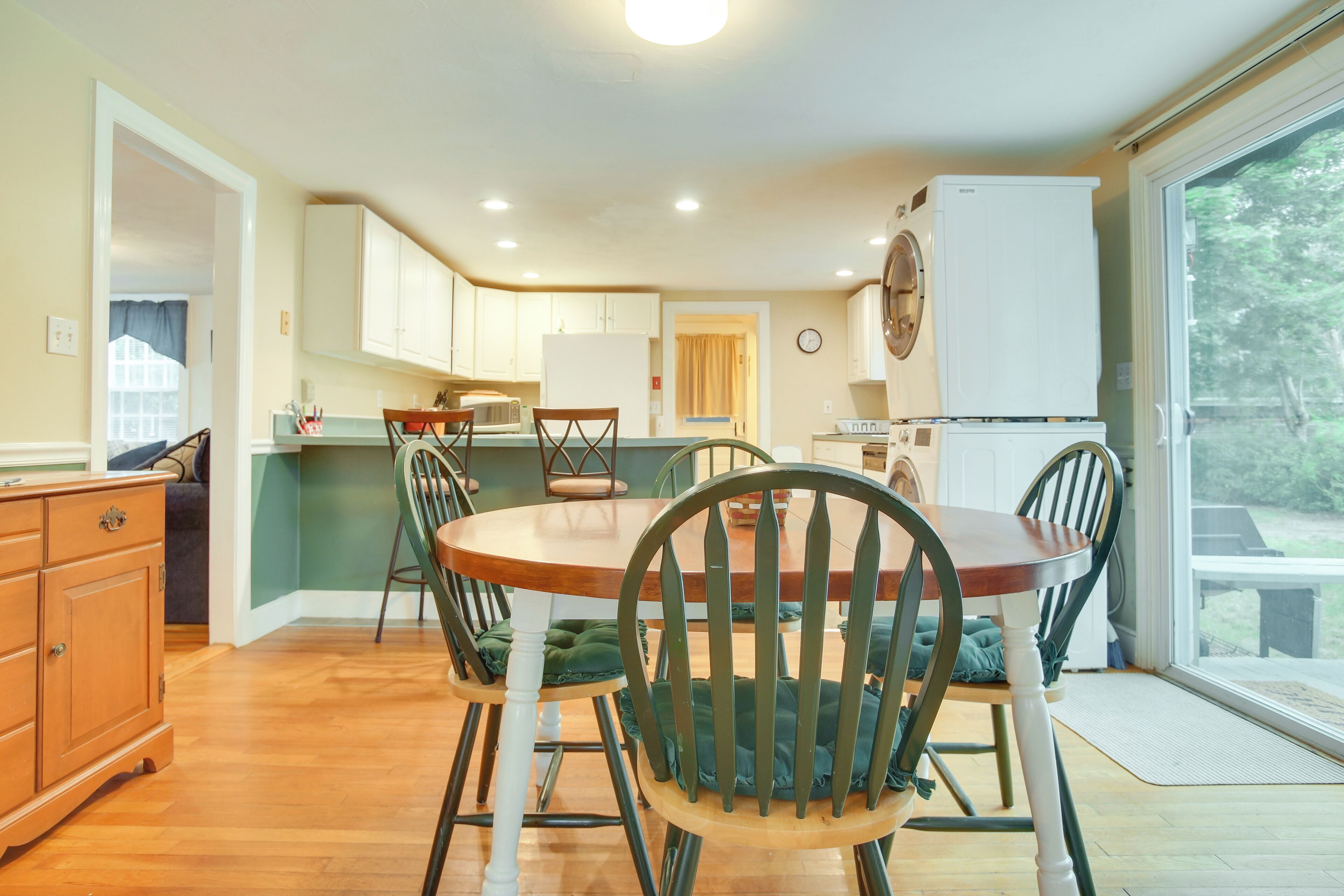 A compact kitchen with wooden cabinets, a dining table with chairs, and a refrigerator.