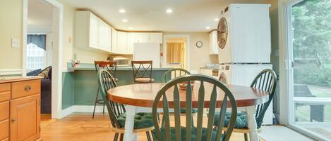 A compact kitchen with wooden cabinets, a dining table with chairs, and a refrigerator.