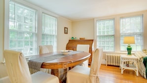 Une salle à manger avec une table ronde en bois, quatre chaises, un radiateur et une lampe.