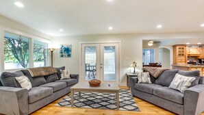 Un salon spacieux avec deux canapés gris, une table basse et un tapis à motifs.