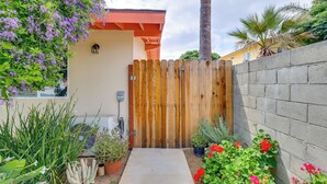 A wooden gate leading to a house with a concrete wall, surrounded by various potted plants and flowers. - Sleek San Fernando Studio ~ 14 Mi to Universal (San Fernando)